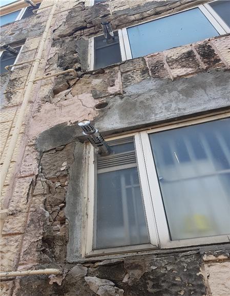 사진1-벽산빌리지 건물의 상당수가 균열이 일어나 철근이 노출되어 있다.